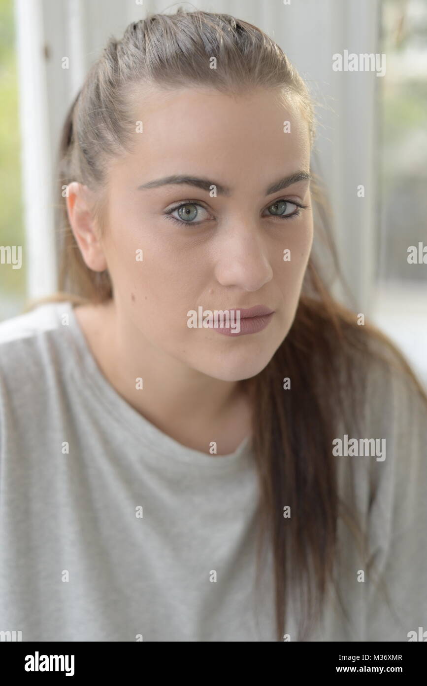 A teenage girl with long hair is alone in a bright room Stock Photo