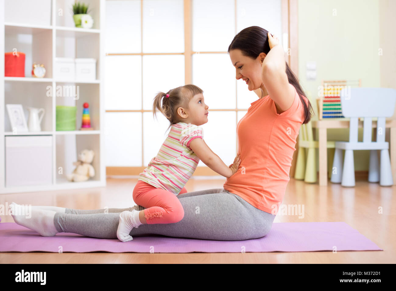 Mom and child doing fitness exercises on mat at home Stock Photo