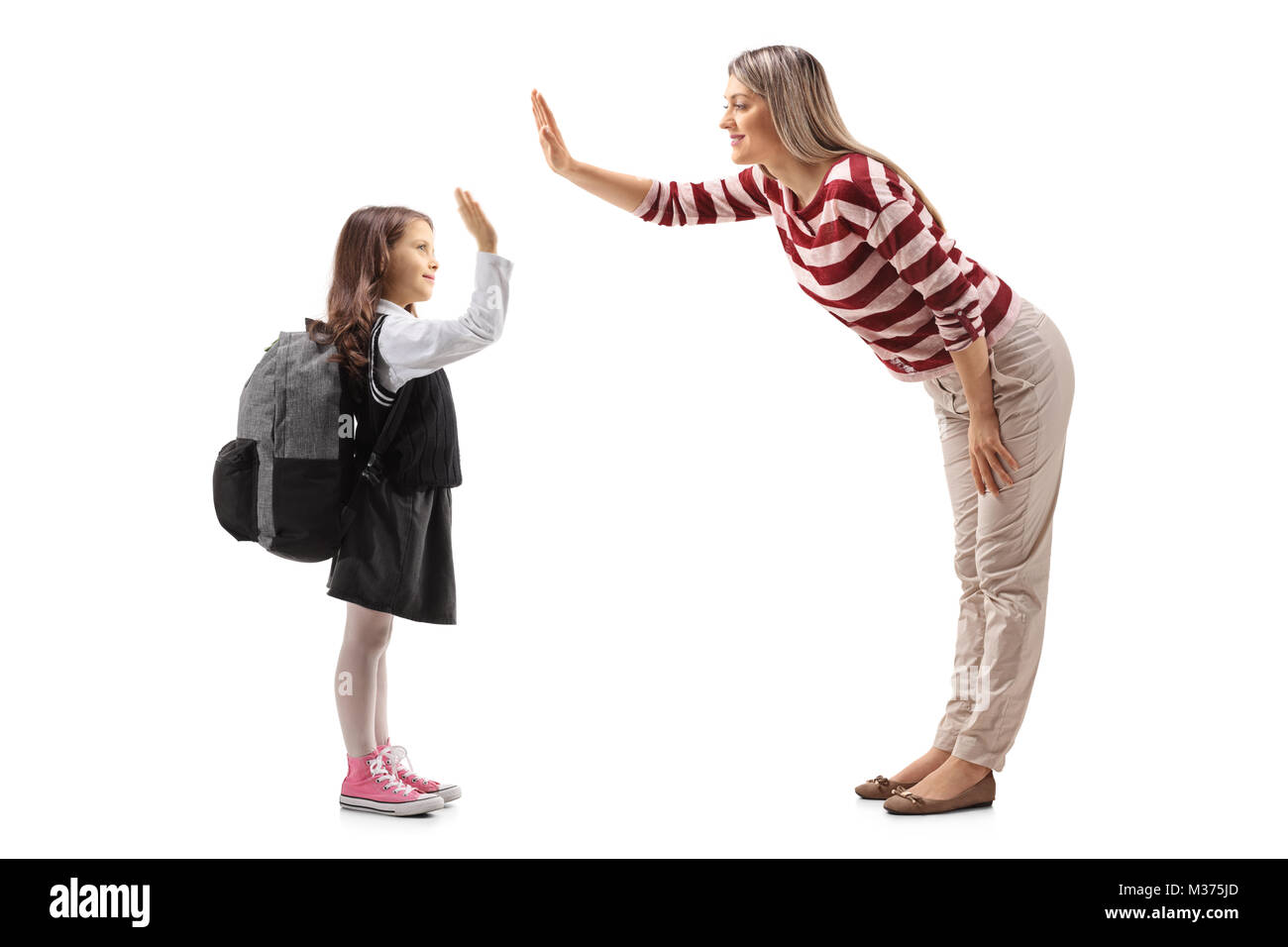 Full length profile shot of a little schoolgirl high-fiving with a young woman isolated on white background Stock Photo