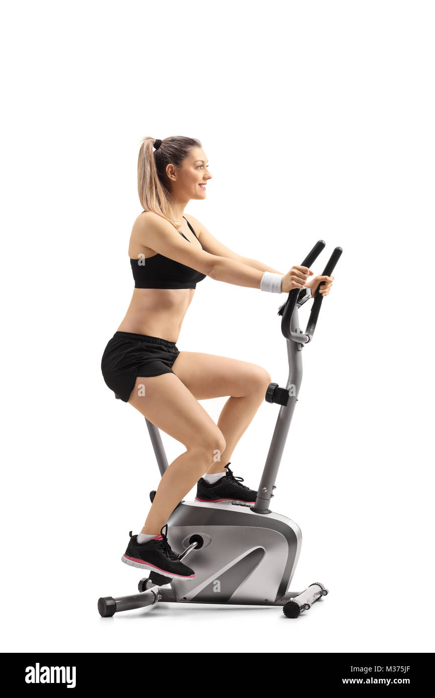 Full length profile shot of a young woman exercising on a cross trainer machine isolated on white background Stock Photo