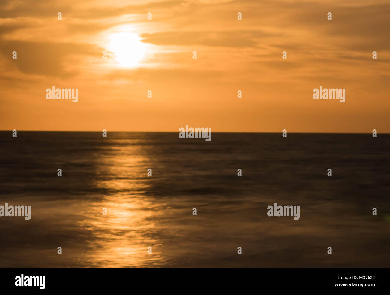 full moon rising into a warm and milky night sky over the ocean Stock Photo