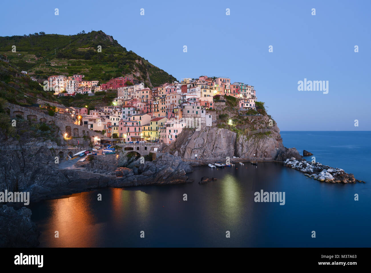 Long exposure of beautiful town of Manarola on the Cinque Terre on Italian coastline after sunset late afternoon on a clear day before blue hour Stock Photo