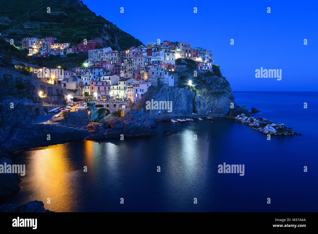 Long exposure of beautiful town of Manarola on the Cinque Terre on the Italian coastline at blue hour after sunset on a clear calm day Stock Photo