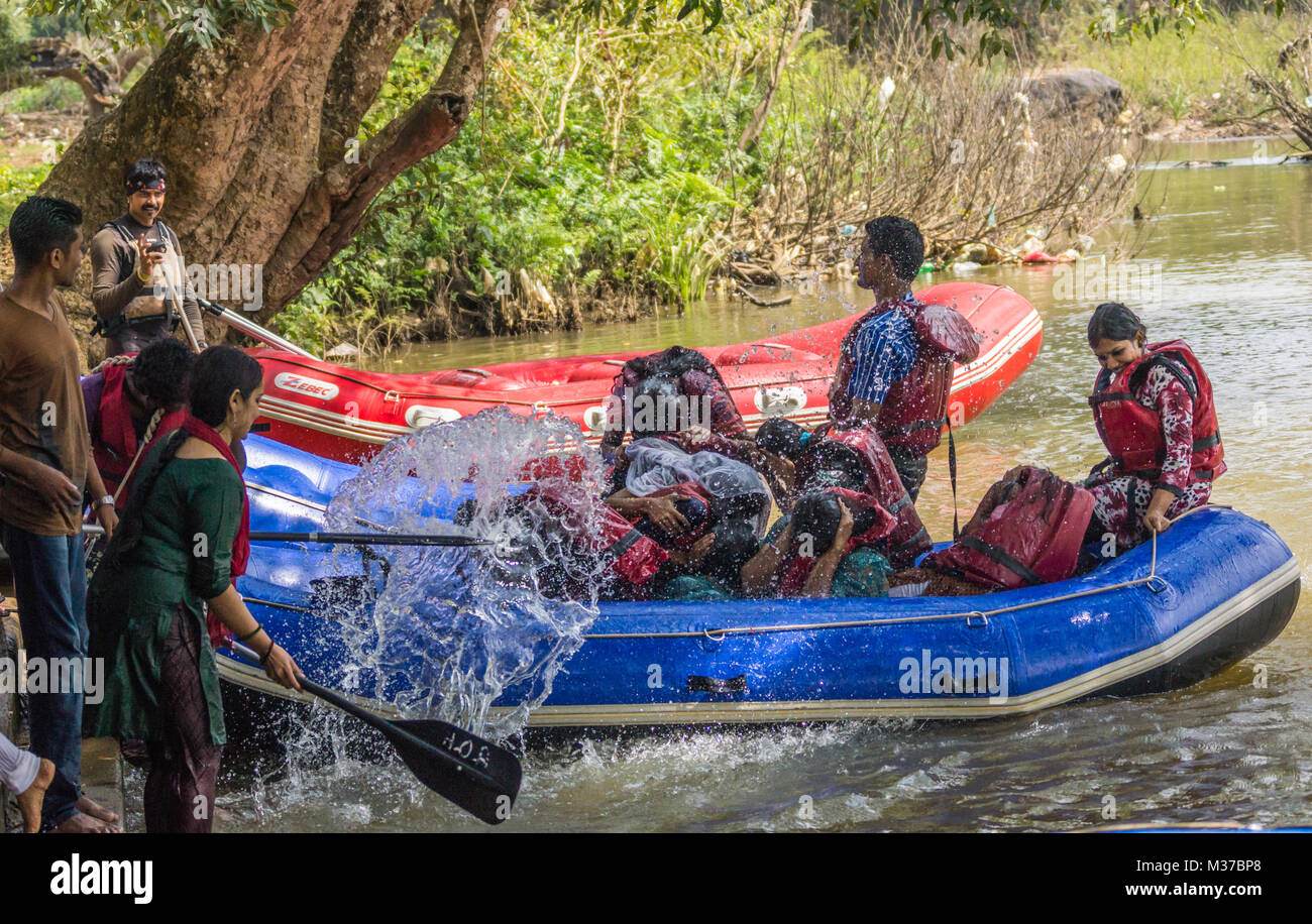 Coorg, India - October 29, 2013: Water rafting in Kaveri River. Passengers of dinghy get splashed by other people. Green shore. Young people having fu Stock Photo