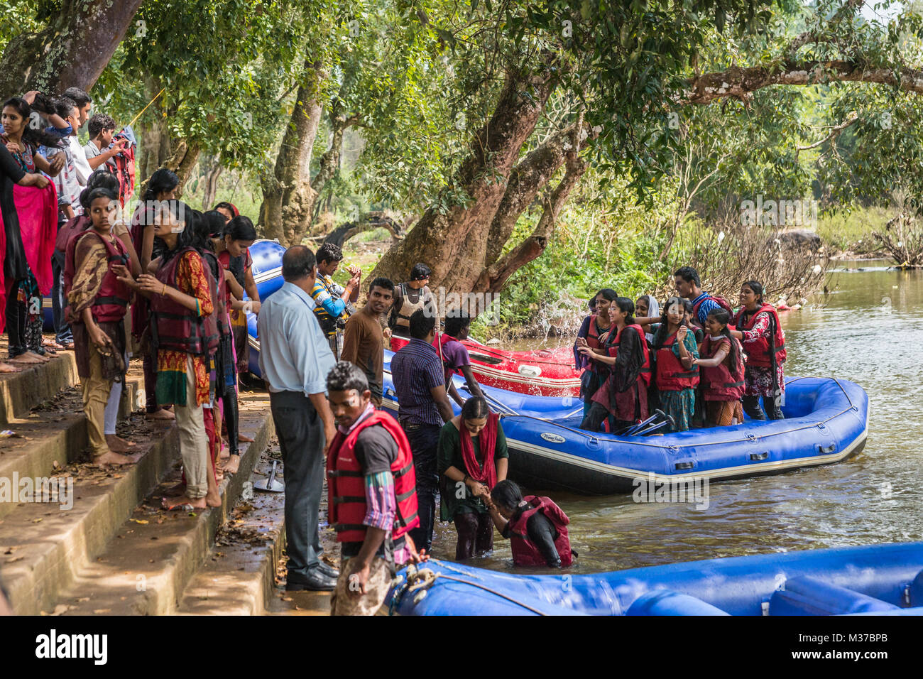 Coorg, India - October 29, 2013: Water rafting in Kaveri River. Dinghy sloops land at stairway on shore. Full of young college-aged girls and boys hav Stock Photo