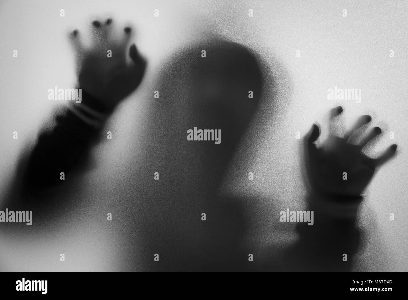 Shadow blur of horror man in jacket with hood.Hands on the glass.Dangerous man behind the frosted glass.Mystery man.Halloween background.Black and whi Stock Photo