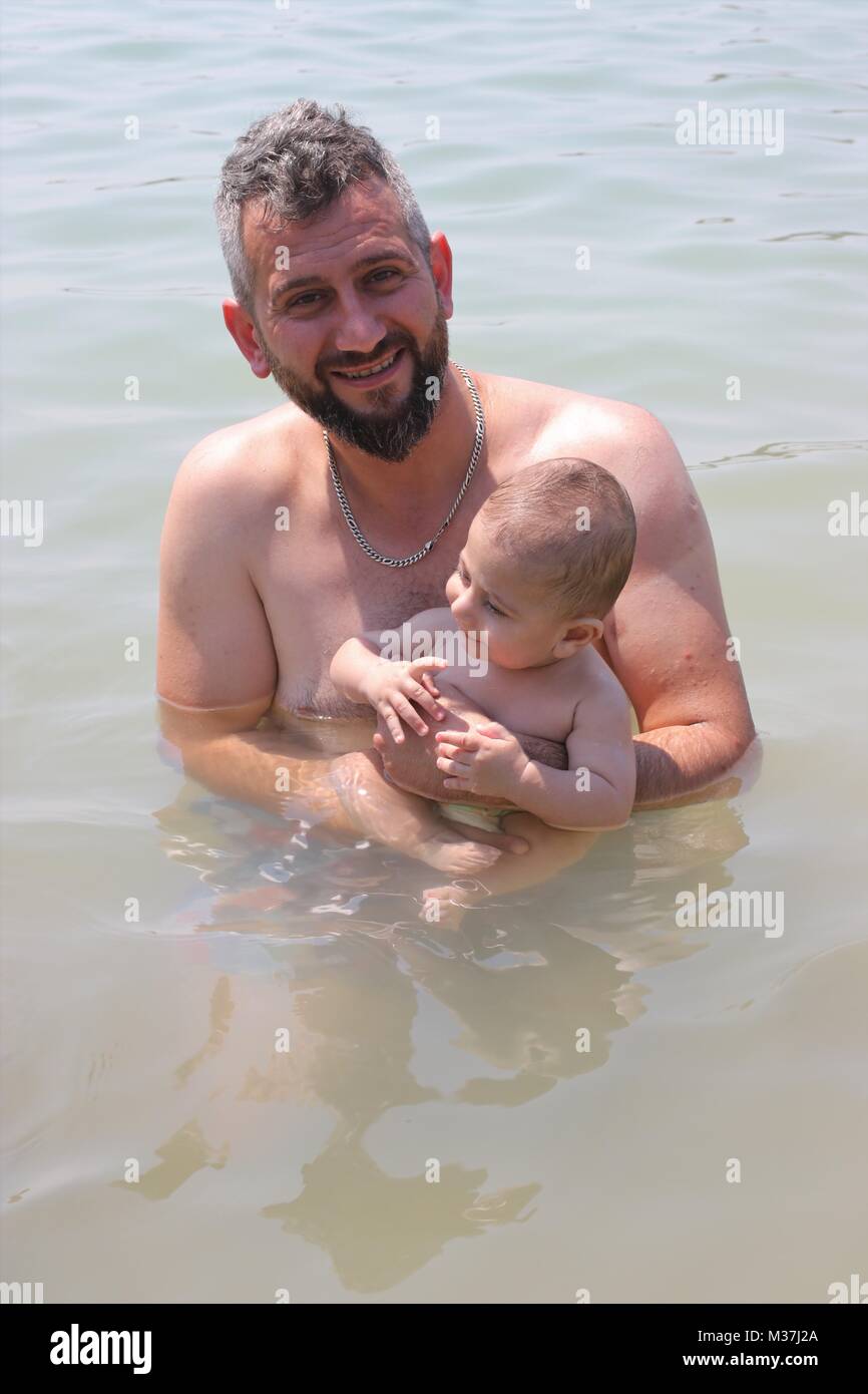 An unknown turkish male in the sea with his baby in ouldeniz, turkey Stock Photo