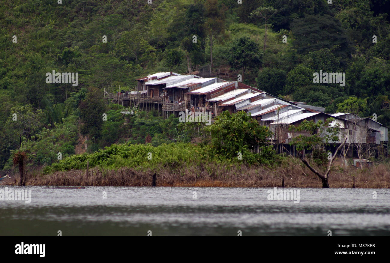 A longhouse is seen amid rainforest on the banks of the Batang Ai National Park reservoir, in Sarawak, Borneo, Malaysia, August 3, 2005. Stock Photo