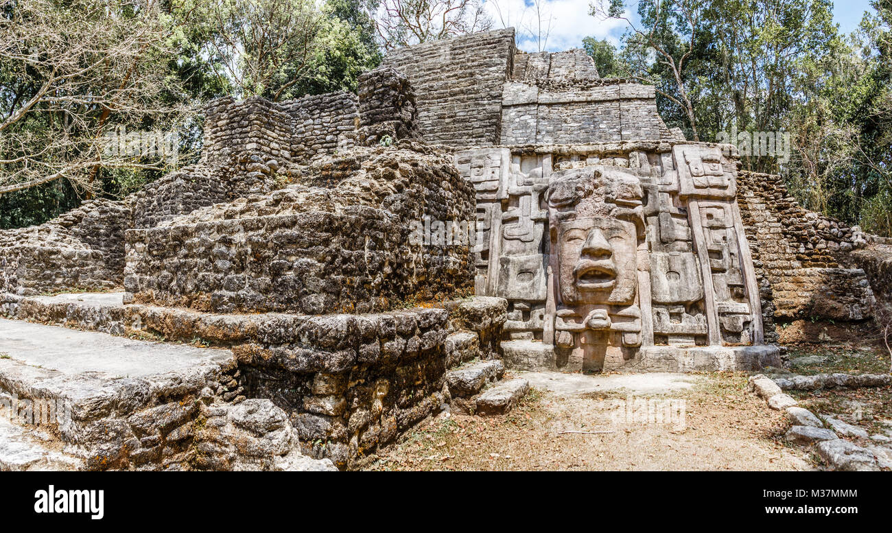 Old ancient stone Mayan pre-columbian civilization pyramid with carved face and ornament hidden in the forest, Lamanai archeological site, Orange Walk Stock Photo