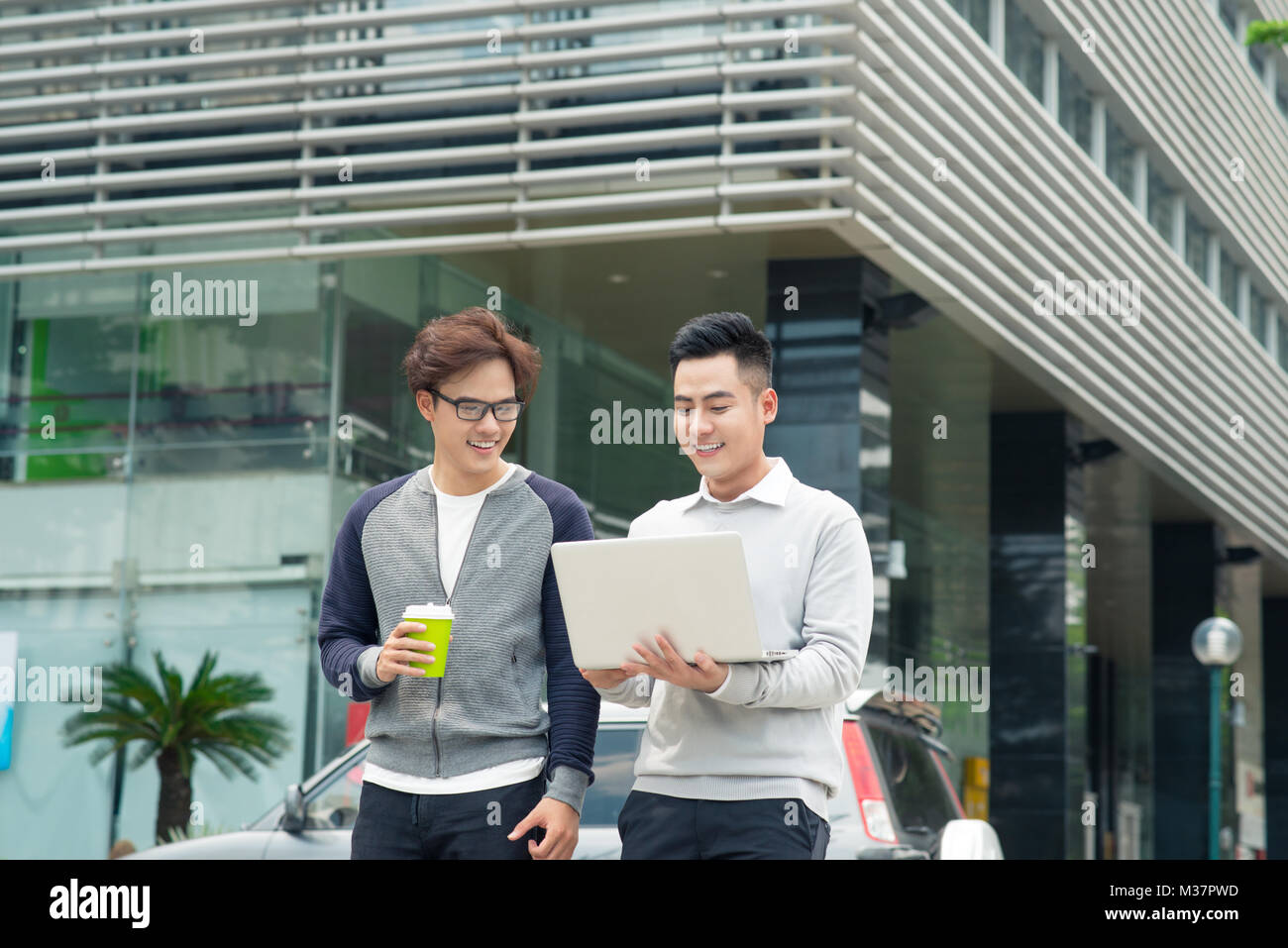 Two smiling young businessmen walking and talking in the city Stock ...