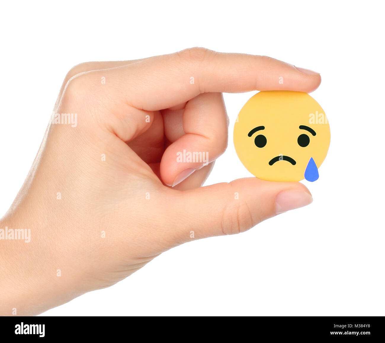 Kiev, Ukraine - September 04, 2017: Hand holds Facebook Sad Empathetic Emoji Reaction, printed on paper. Facebook is a well-known social networking se Stock Photo