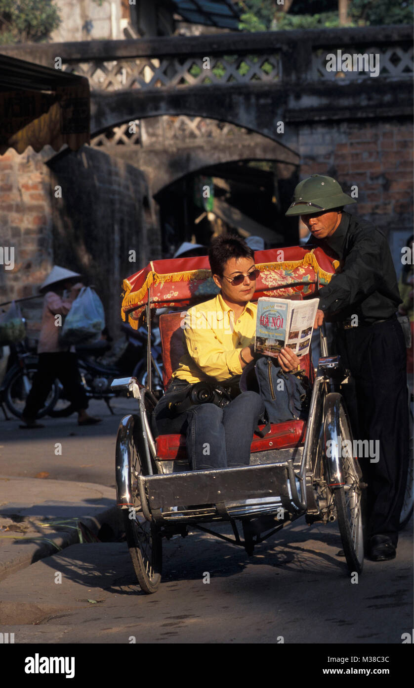 Vietnam. Hanoi. Old quarter. Rickshaw. Cyclo driver. Tourist, woman  looking at map. Stock Photo