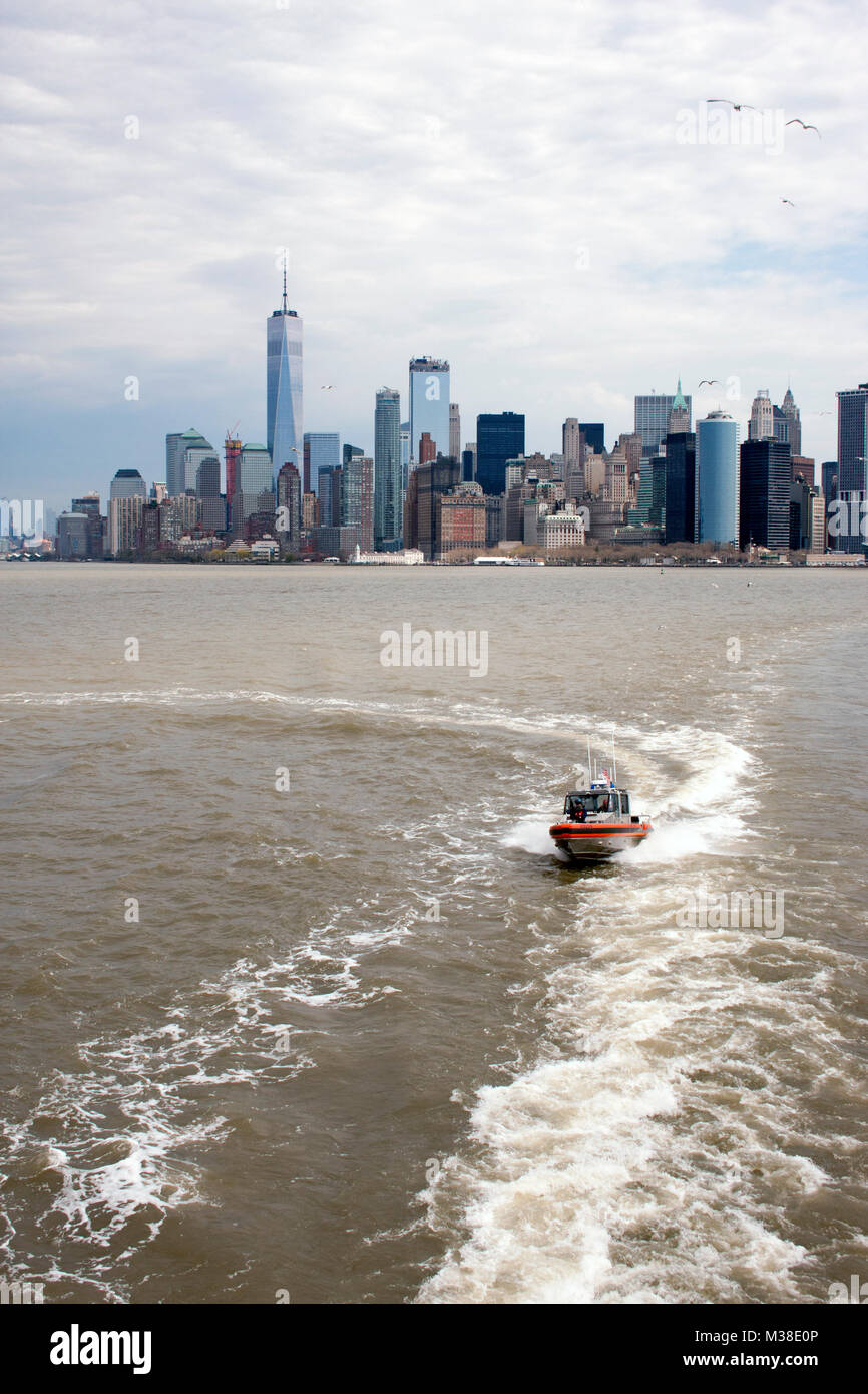 Coast Guard escort follows the State Island Ferry, with a view of Manhattan Stock Photo