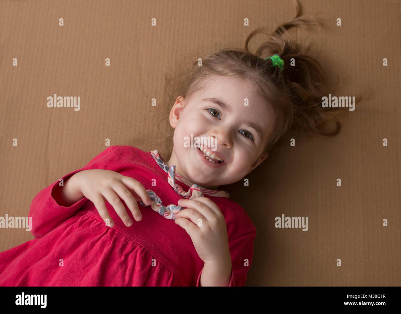 Clouse-up portrait of cheerful little girl on the background of a cardboard box Stock Photo