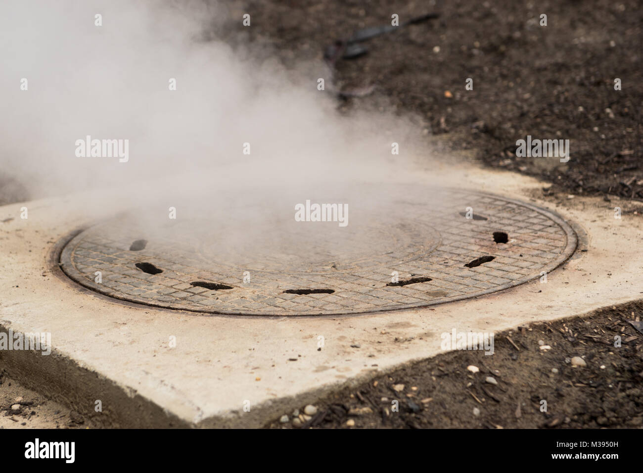 Hot white steam coming out of metal manhole or metal hatch Stock Photo