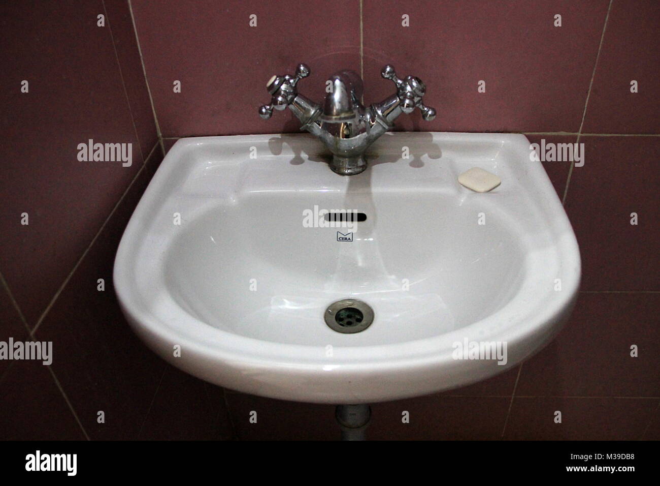Elegant, white washbasin with fittings fixed on brown tiled bathroom wall Stock Photo Alamy