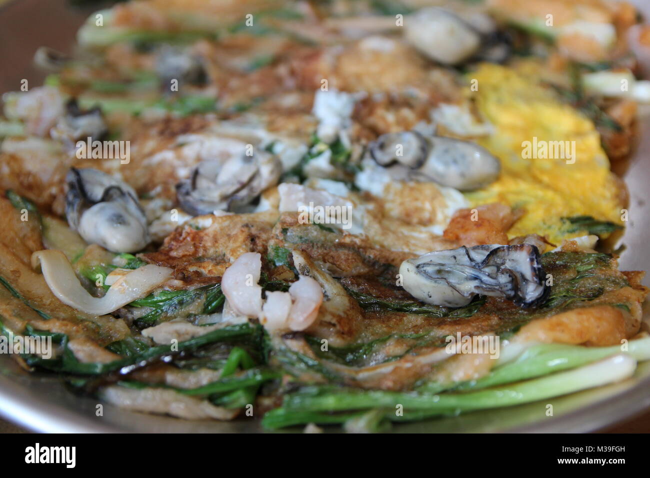Focus on oyster on the Korean pancake with the leek and egg at Korean