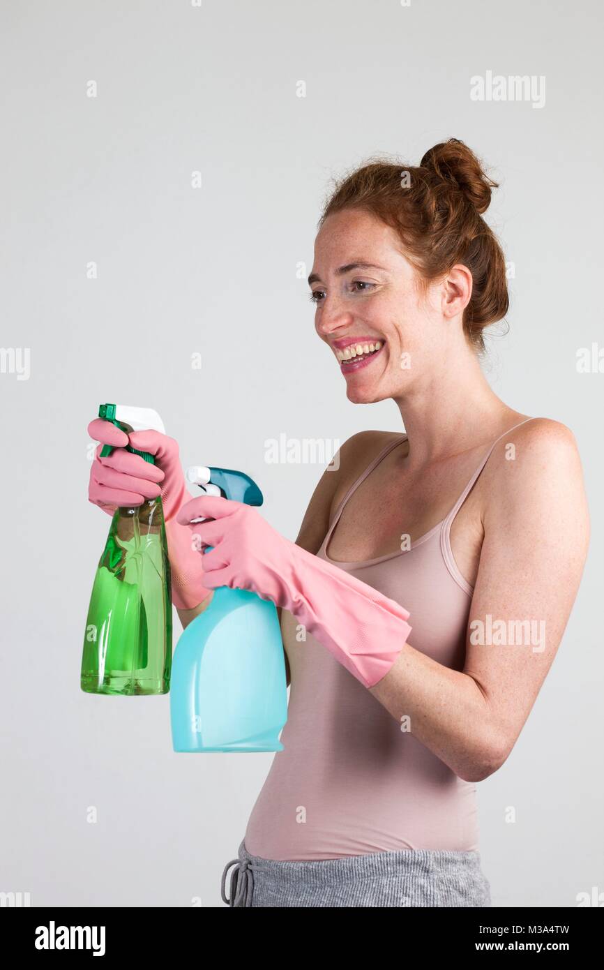MODEL RELEASED. Smiling woman with protective gloves holding cleaning materials. Stock Photo