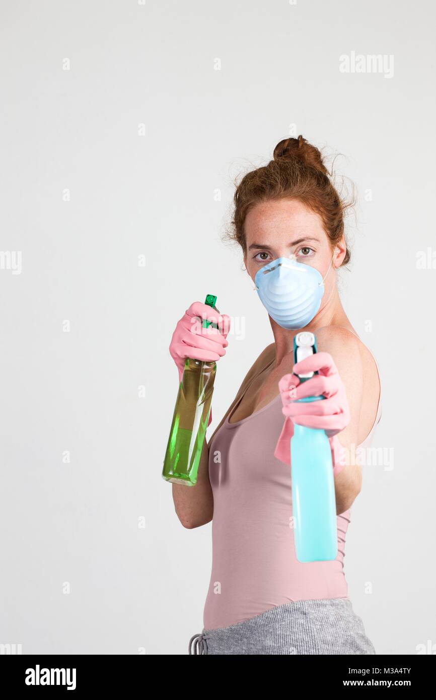 MODEL RELEASED. Woman wearing face mask and gloves holding cleaning materials in her hands. Stock Photo