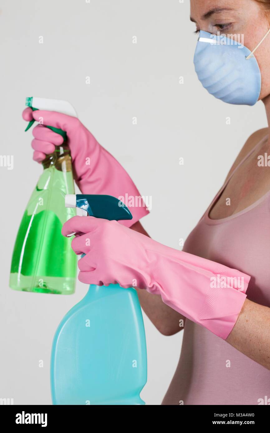 MODEL RELEASED. Close-up of woman wearing face mask holding cleaning materials in her gloved hands. Stock Photo