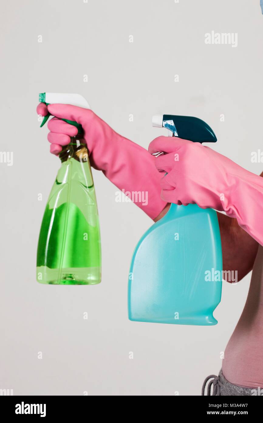 MODEL RELEASED. Close-up of hands with pink gloves holding cleaning materials. Stock Photo