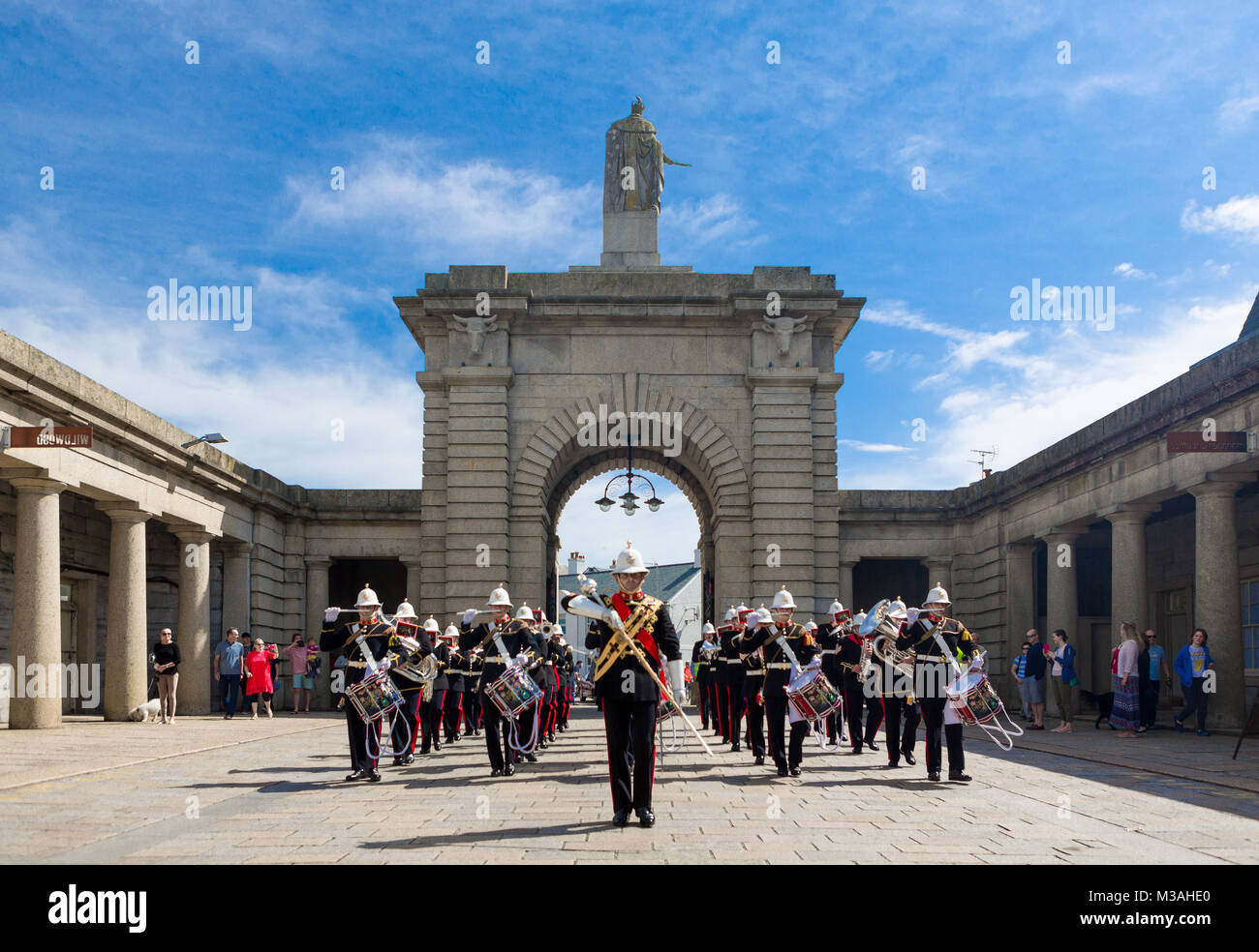 The Band of HM Royal Marines march through Plymouth's Royal William Yard Archway on a bright sunny day. Stock Photo