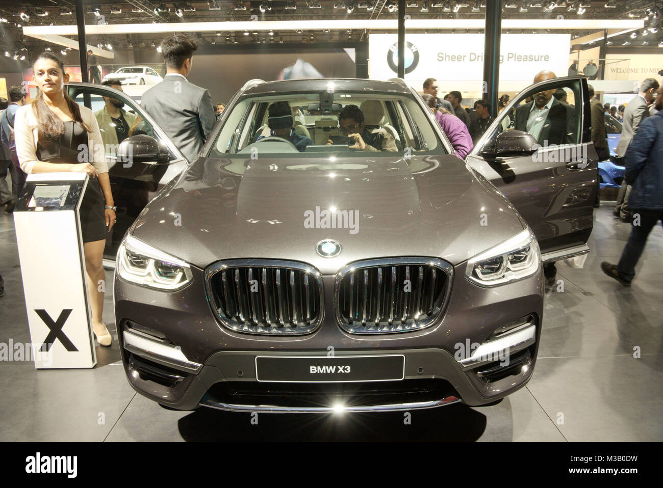 Greater Noida, India. 9th February 2018. Visitors try to get a feel of BMW X3 20d Luxury Line car on display at the Auto Expo 2018 at India Expo Mart in Greater Noida, India. The Auto Expo is a biennial event and is being held during 9th to 14th February 2018. Credit: Karunesh Johri/Alamy Live News. Stock Photo