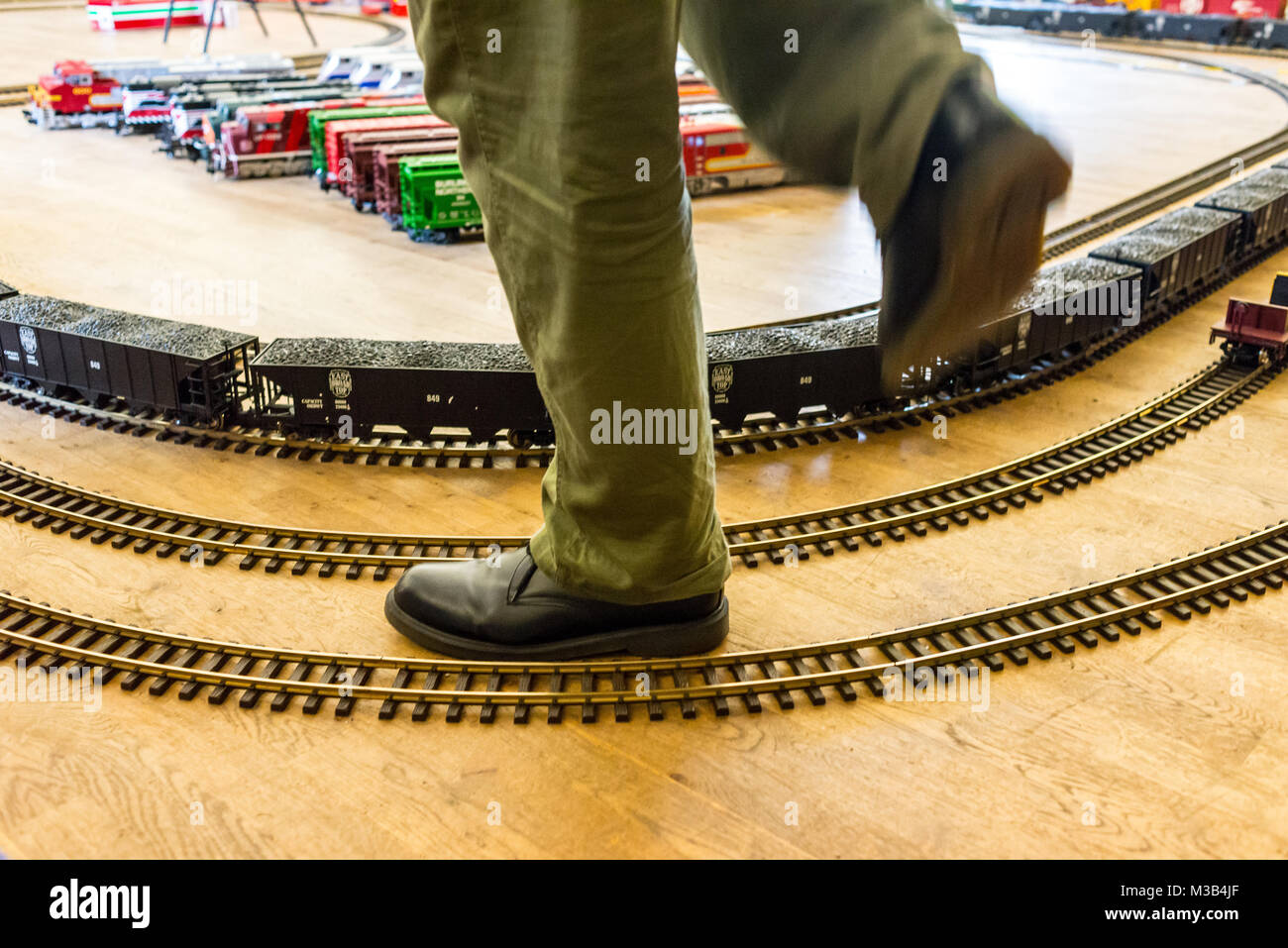 Man's foot wearing a boot stepping over a super sized train set exhibition. Stock Photo