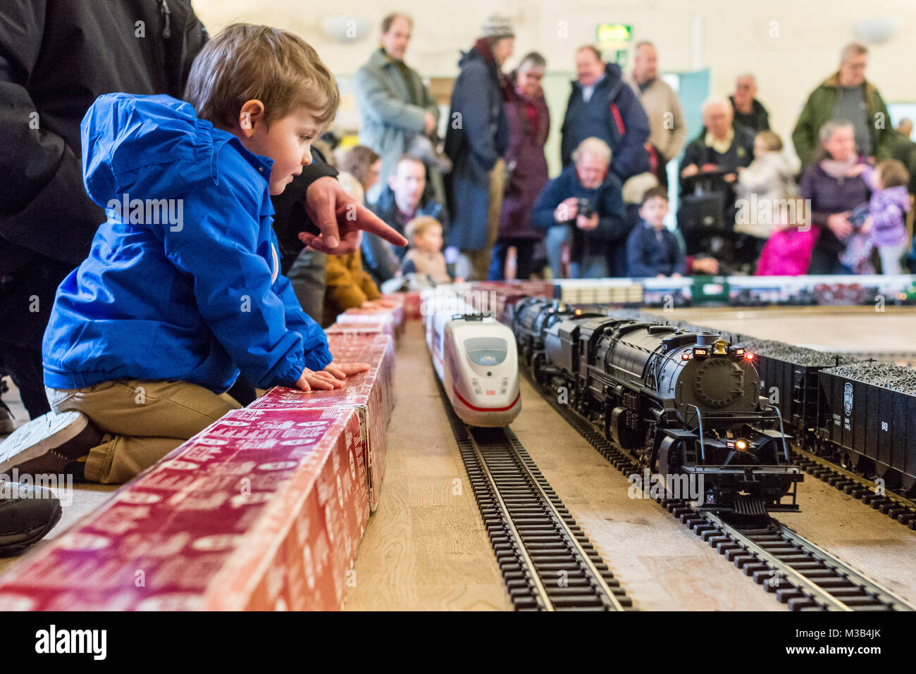 A young boy looking in awe at a super sized train set on exhibition in the church hall at Fordingbridge, Hampshire, UK. The model railway is a draw for big and little people alike. Stock Photo