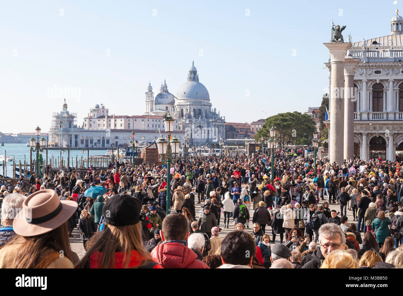 Venice, Veneto, Italy, 10th February 2018. Crowds on Riva degli Schiavoni and Piazzetta San Marco on the last weekend of the carnival with Basilica di Santi Maria della Salute in the background. Eighty thousand people are thought to have attended the carnival on Saturday.. Credit MCpics/Alamy Live News Stock Photo