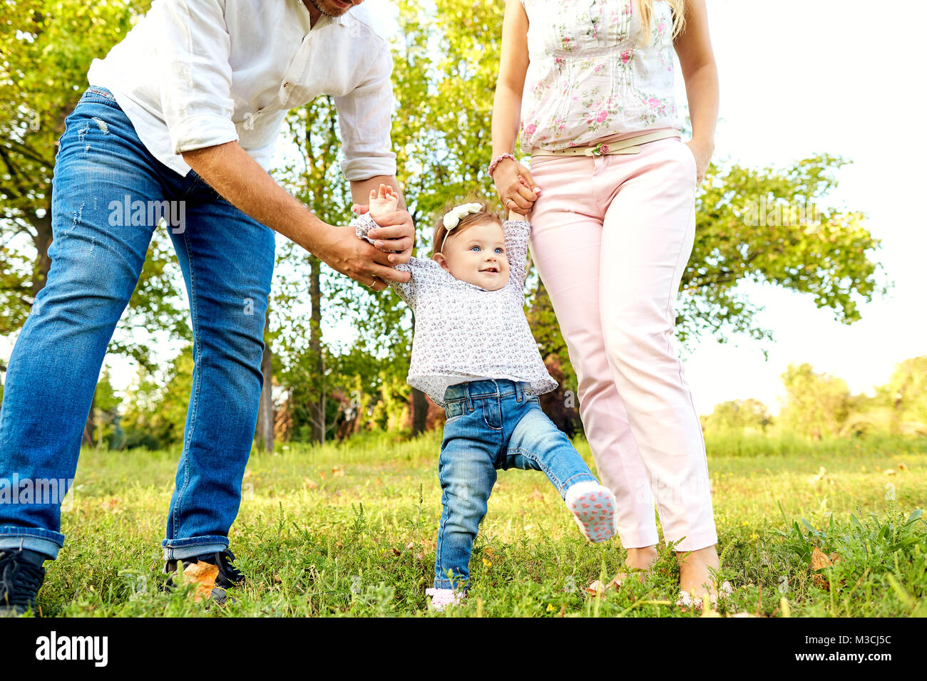The first steps of the baby. Parents are teaching their child to Stock Photo