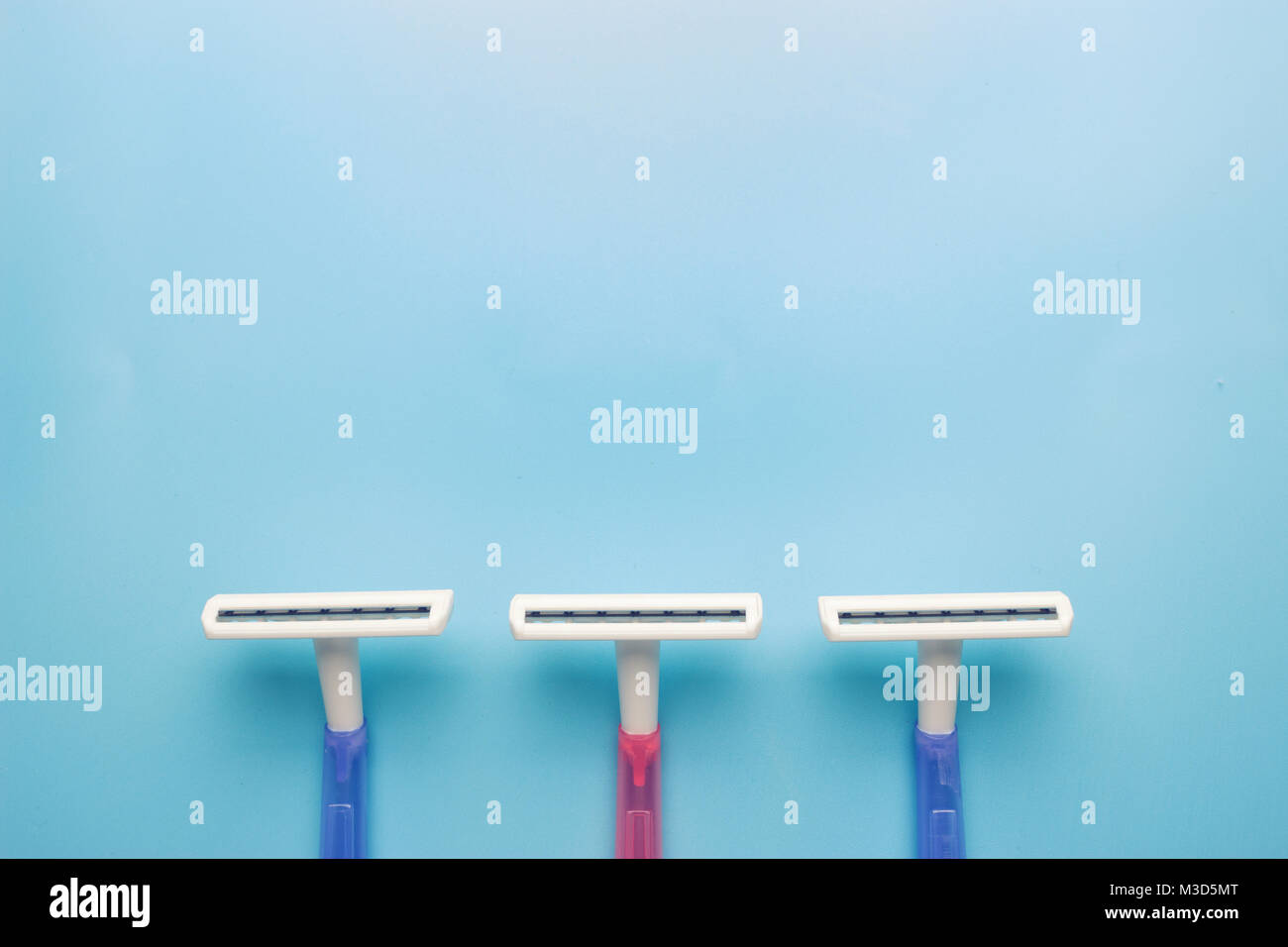 Female disposable razor on blue background with copy space Stock Photo