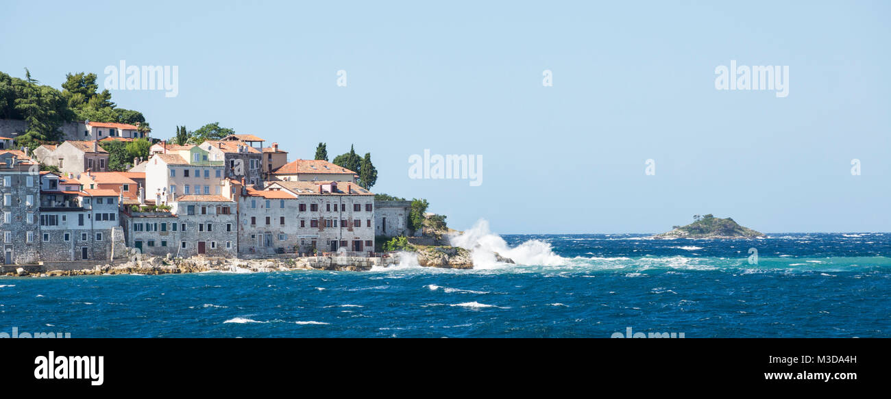 A photograph of Rovinj, Croatia taken during a summer storm with waves crashing onto the shoreline. Stock Photo