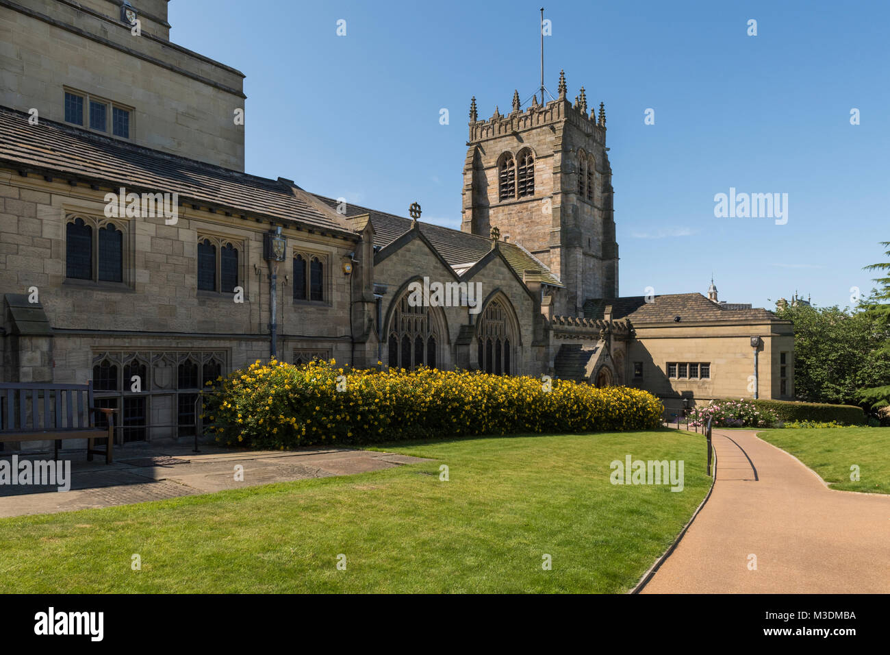 Under a deep blue sky, an exterior view of Bradford Cathedral with its squat, square tower & peaceful gardens - Bradford, West Yorkshire, England, UK. Stock Photo
