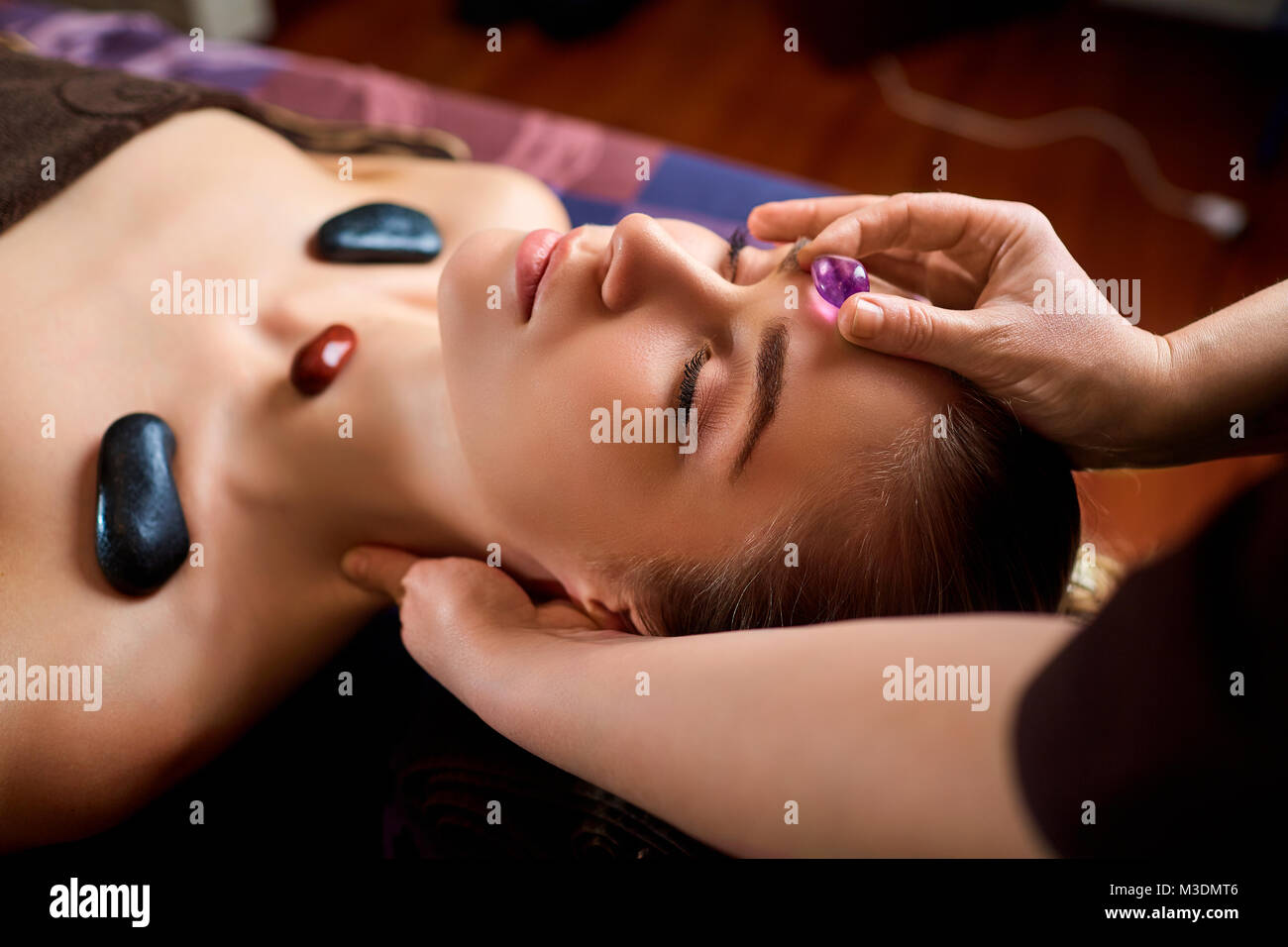 Stone massage is a facial massage for a woman. Stock Photo