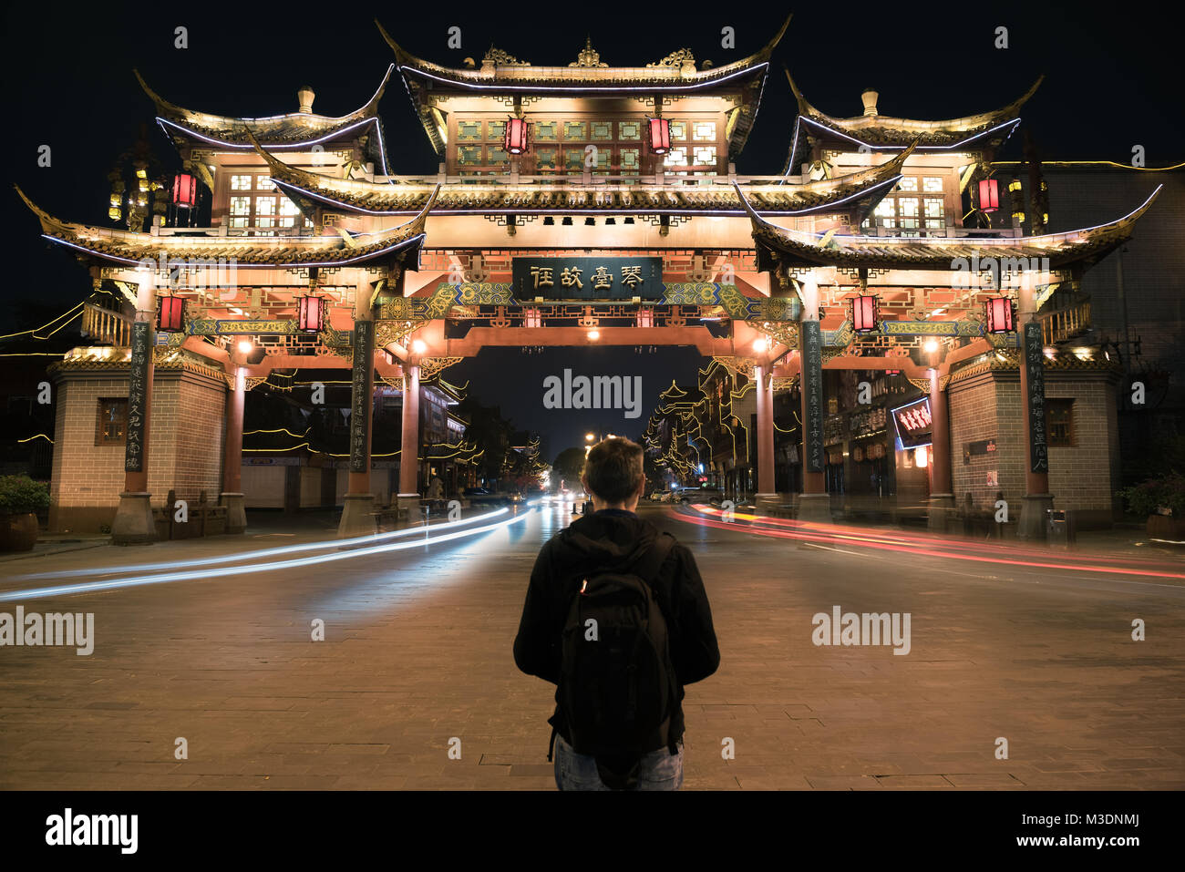 Chengdu, China -Oct,8,2017- A man stand in front of the ancient Chinese gate in Qintai Road historic district at night in Chengdu,China Stock Photo