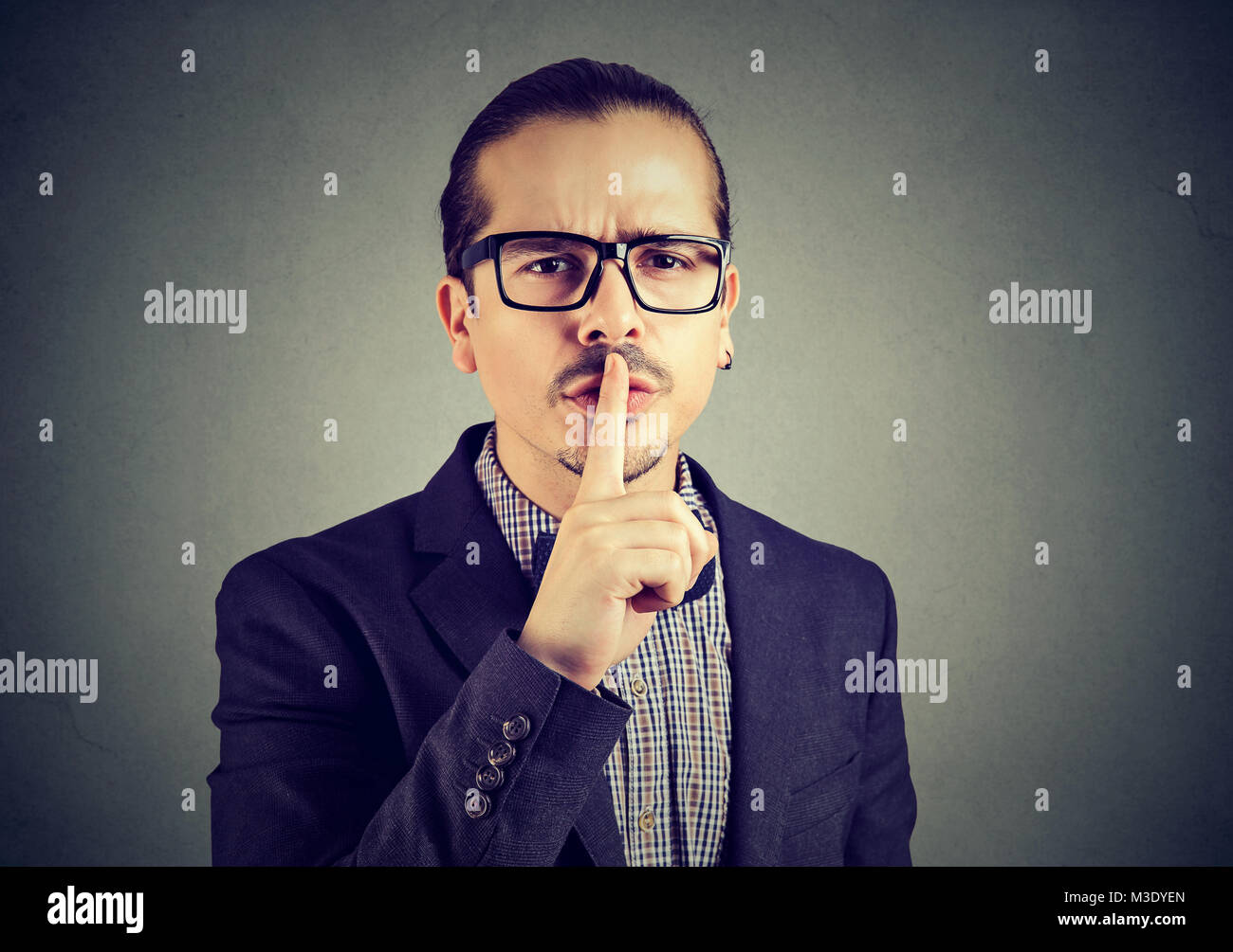 Formal serious man in eyeglasses doing quiet gesture looking at camera. Stock Photo