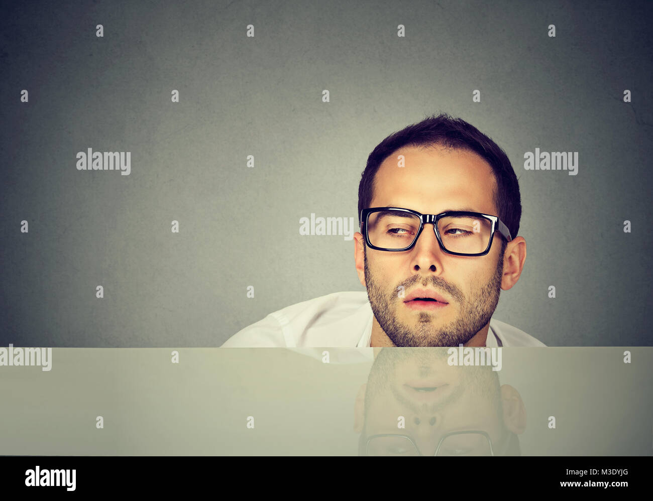 Young casual man in eyeglasses looking exhausted while working while day long. Stock Photo