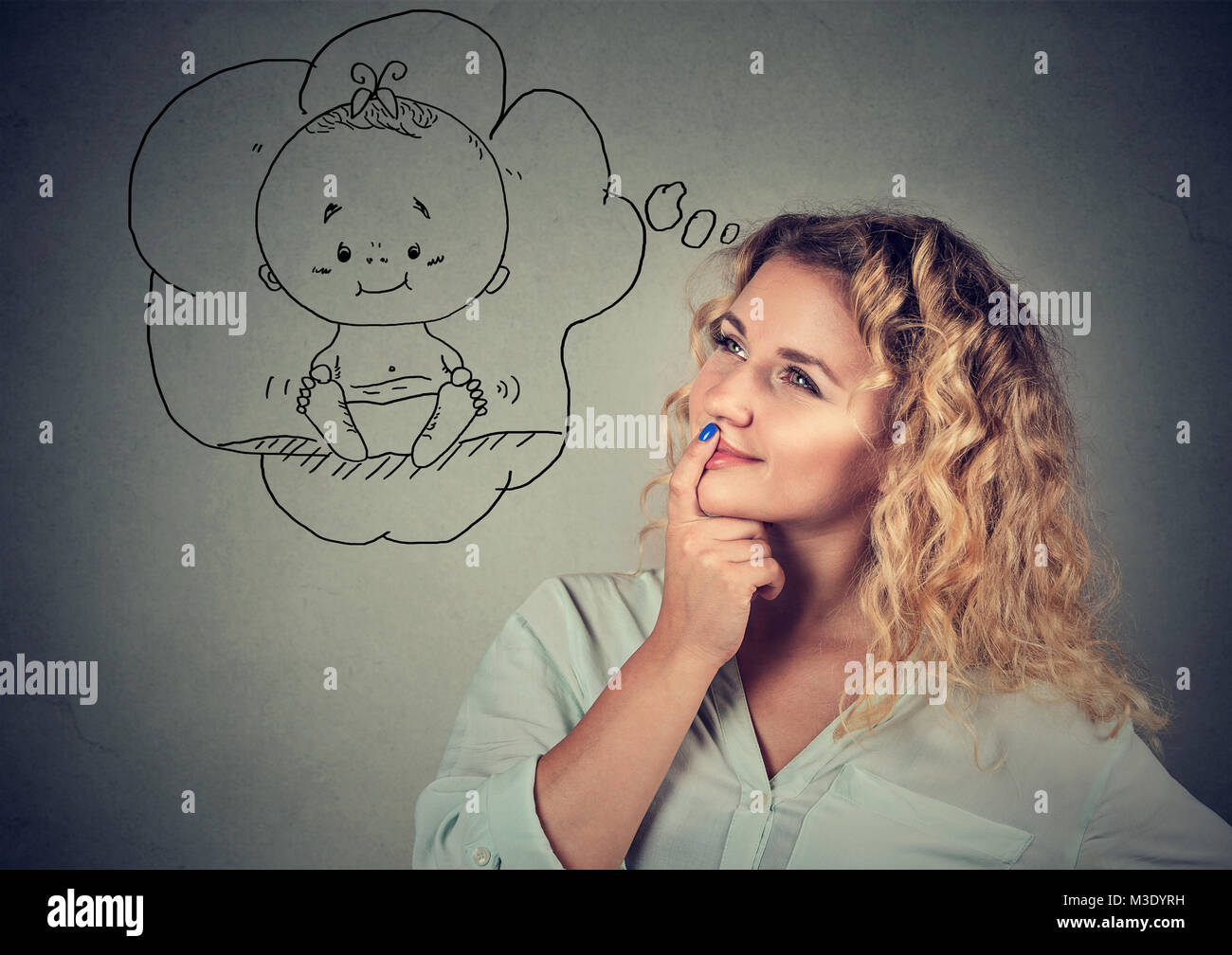 Content young woman is taken with idea of having child while posing on gray. Stock Photo