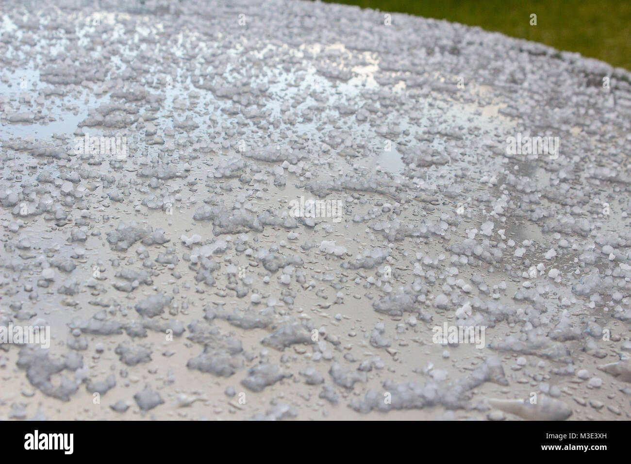 Frozen hailstones on a silver car roof following a cold winter shower Stock Photo