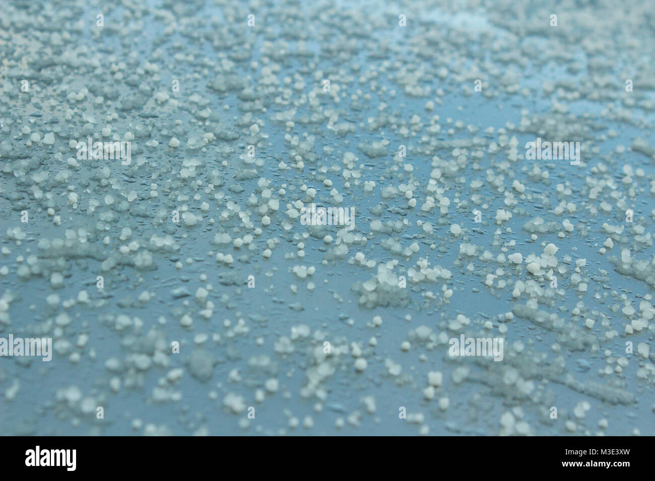 Frozen hailstones on a silver car roof following a cold winter shower Stock Photo