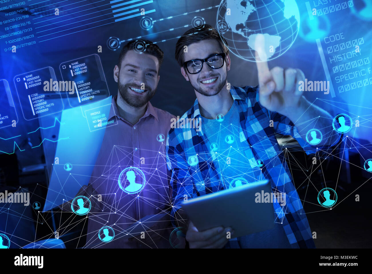Positive programmers feeling glad while working with transparent screen Stock Photo