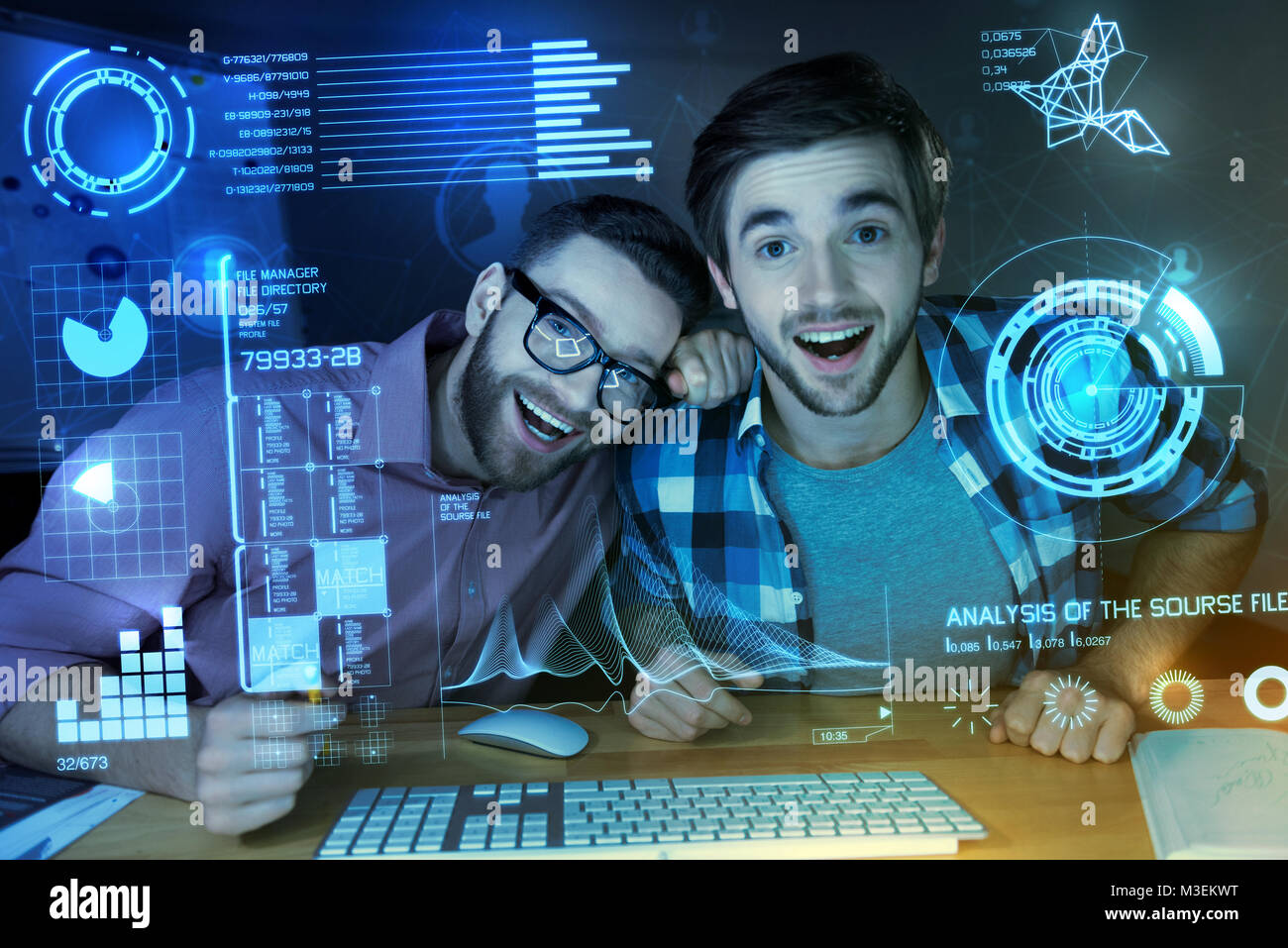 Positive programmers laughing while looking at the modern transparent screen Stock Photo