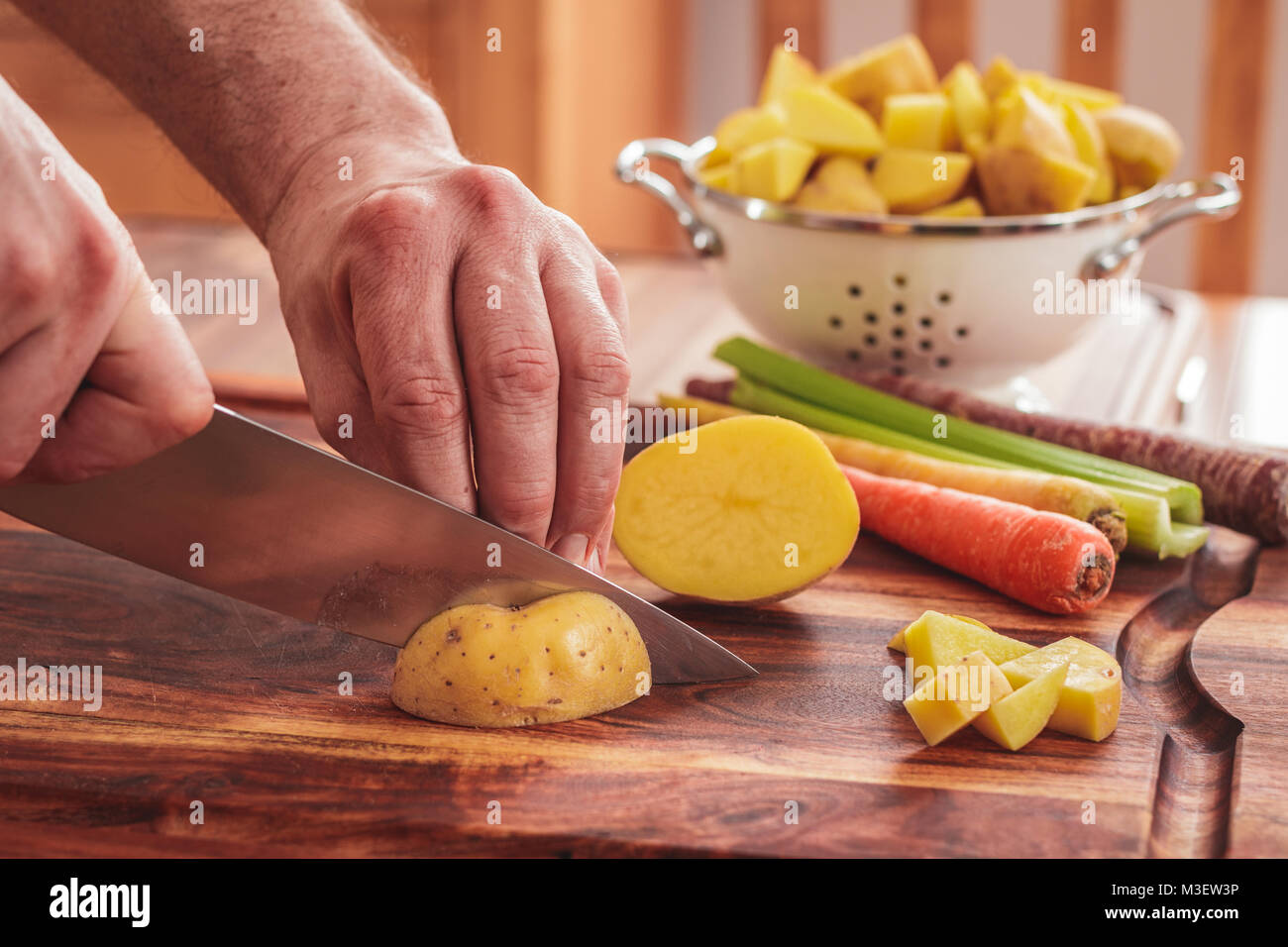 Chopping potatoes for homemade chicken and white bean soup.  Ingredients include potatoes, carrots, and celery. Stock Photo