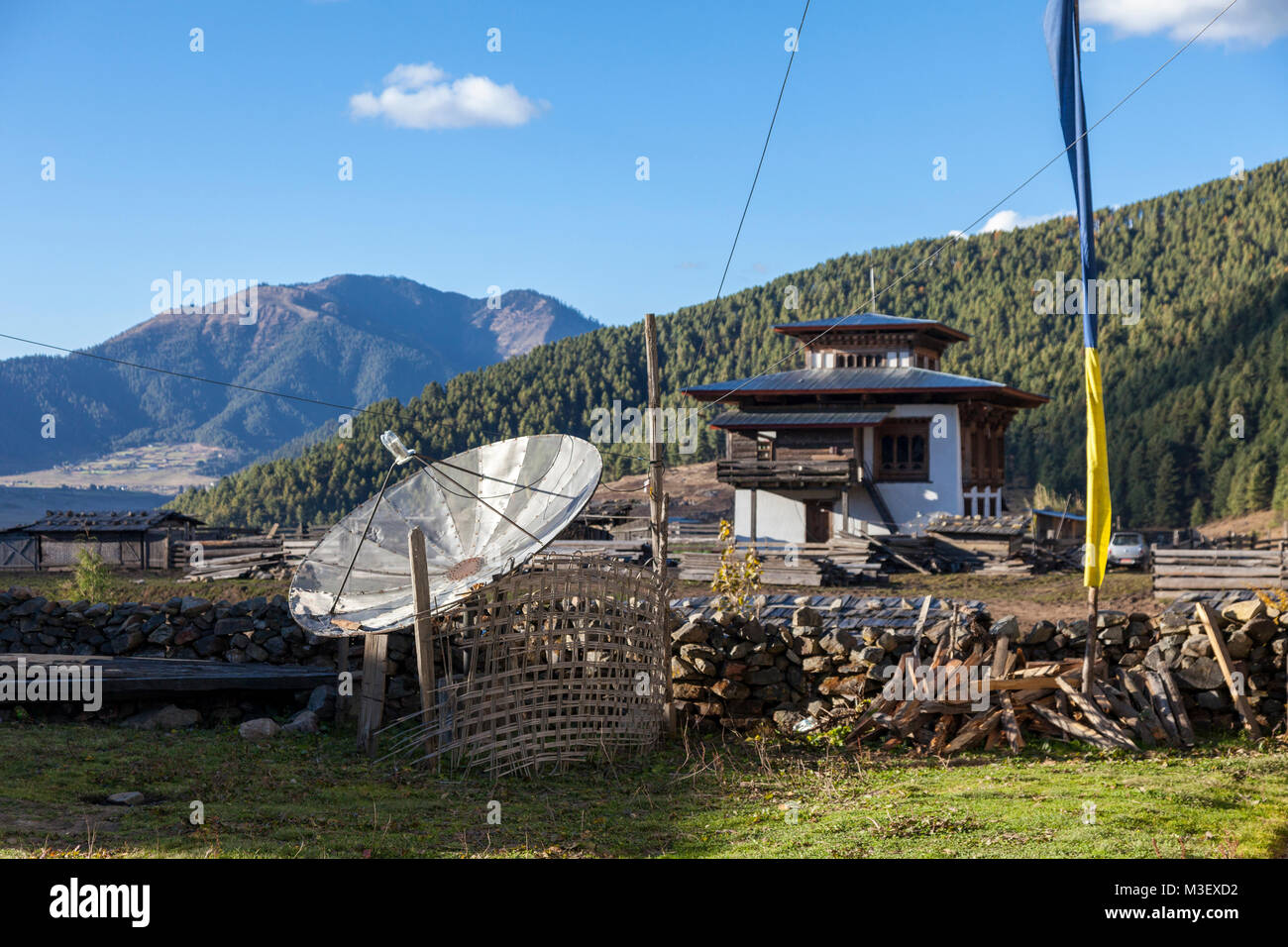 Phobjikha, Bhutan.  Satellite Dish in Foreground, Typical Middle-class Rural Farmhouse in Background,  Kikorthang Village. Stock Photo