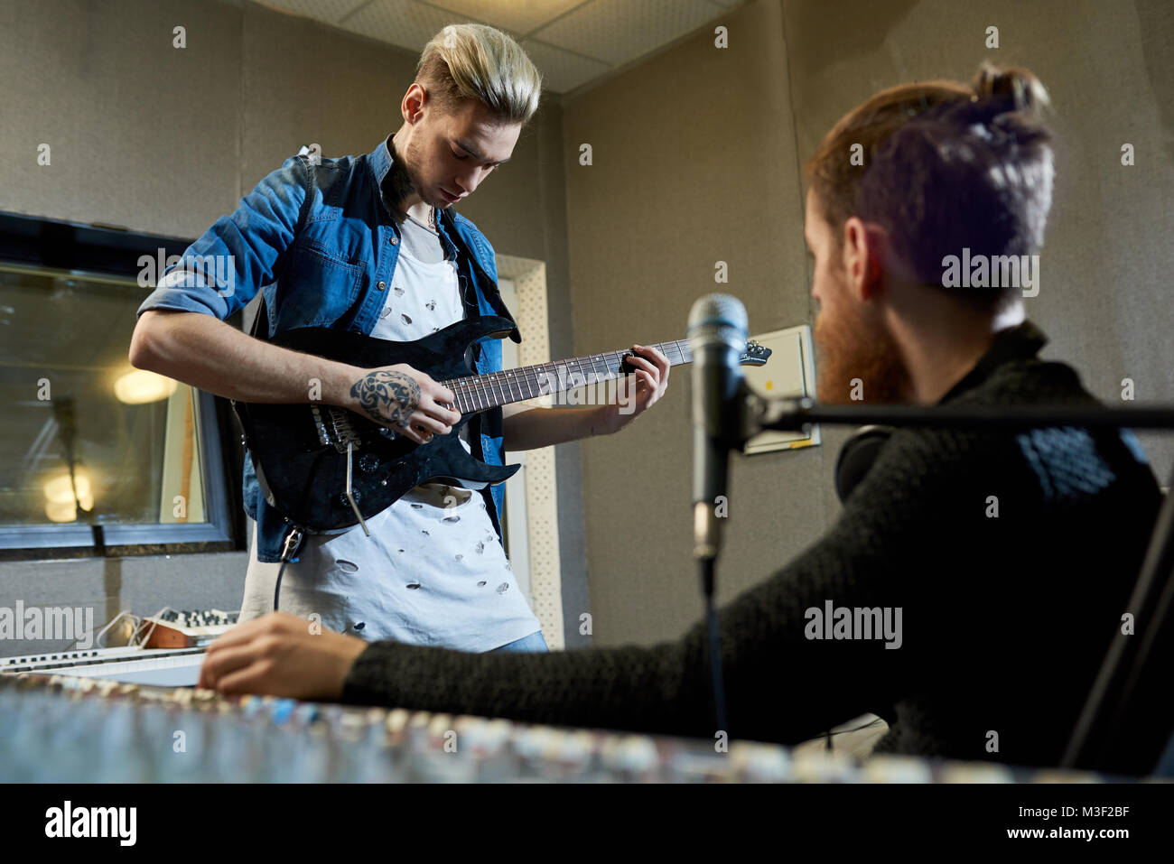 Rockstar guitarist composing new song with producer Stock Photo Alamy