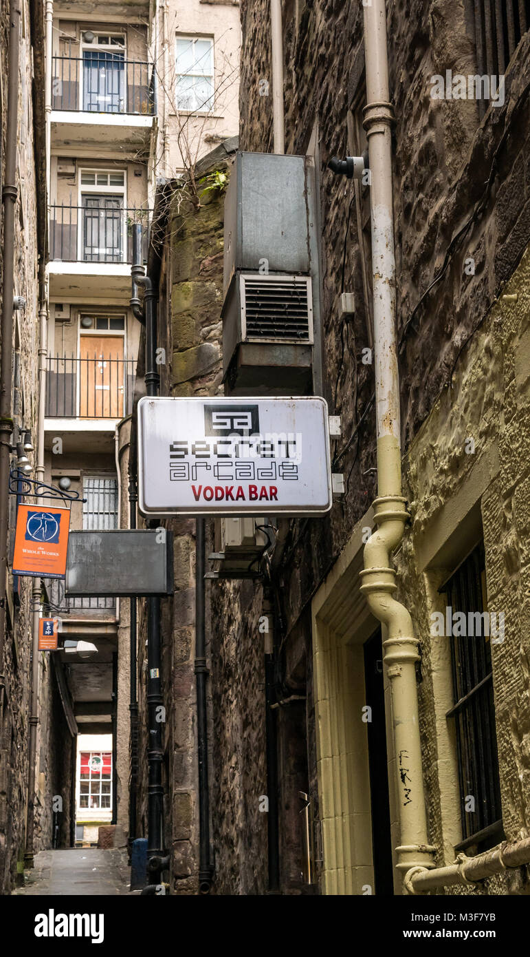 Alley called Jackson's Close, Cockburn Street, Edinburgh, Scotland, UK, with flat doors in tenement, signs and Secret Arcade vodka bar Stock Photo