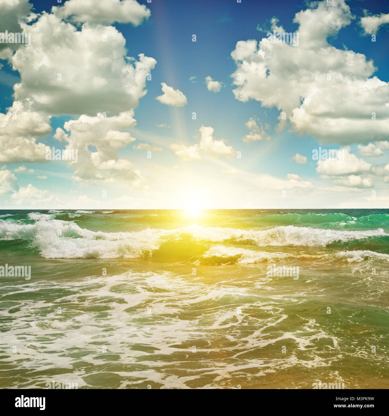 ocean, sandy beach, blue sky and sunrise Stock Photo - Alamy