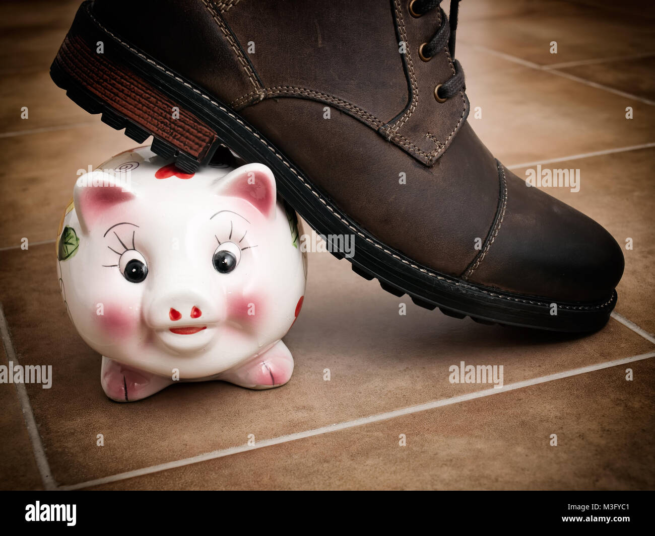 A shoe treads piggy bank as a metaphor about savings problems. Stock Photo