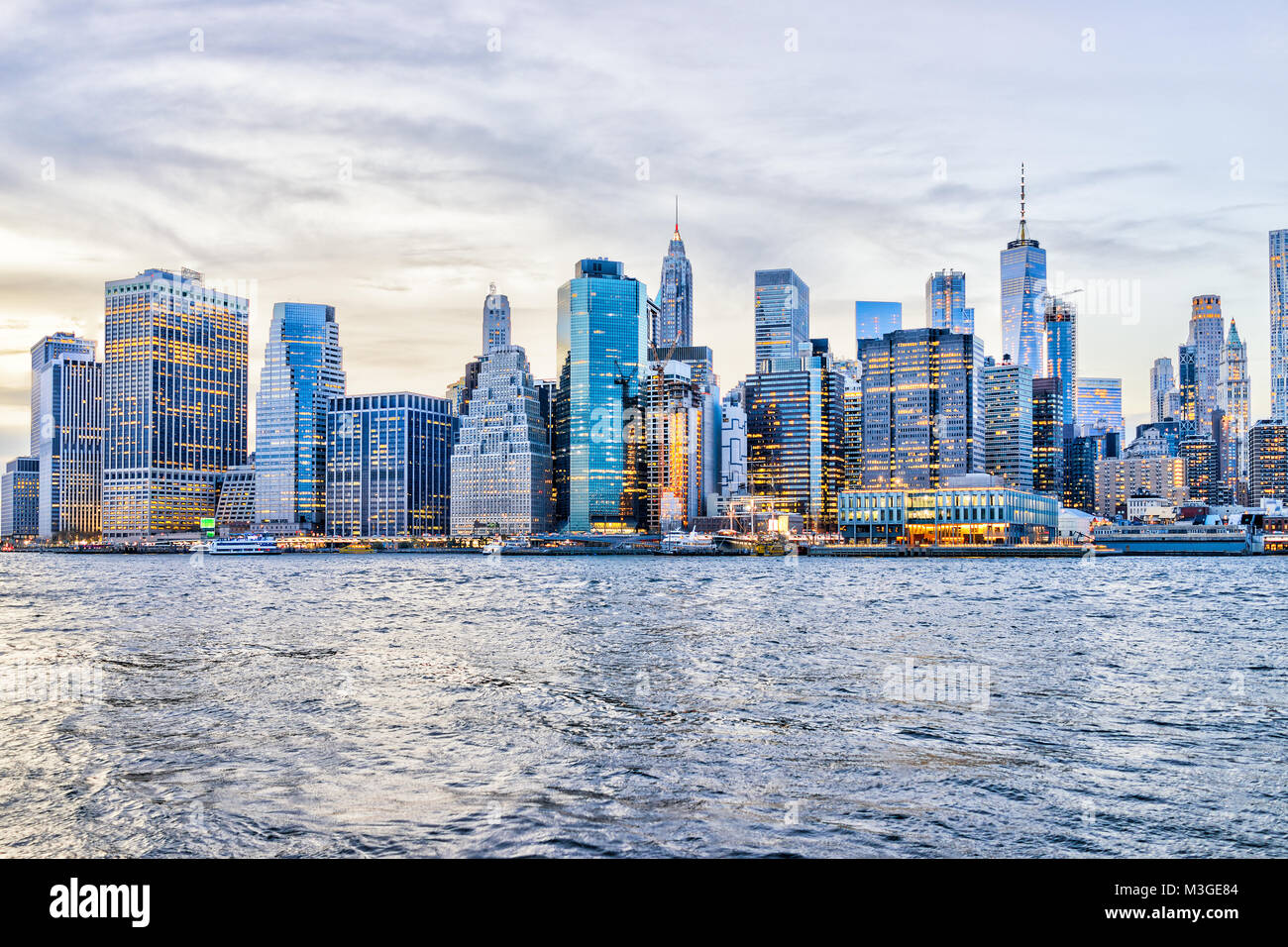 View of NYC New York City downtown lower financial district skyscrapers, east river, cityscape skyline during evening sunset, dusk, twilight Stock Photo